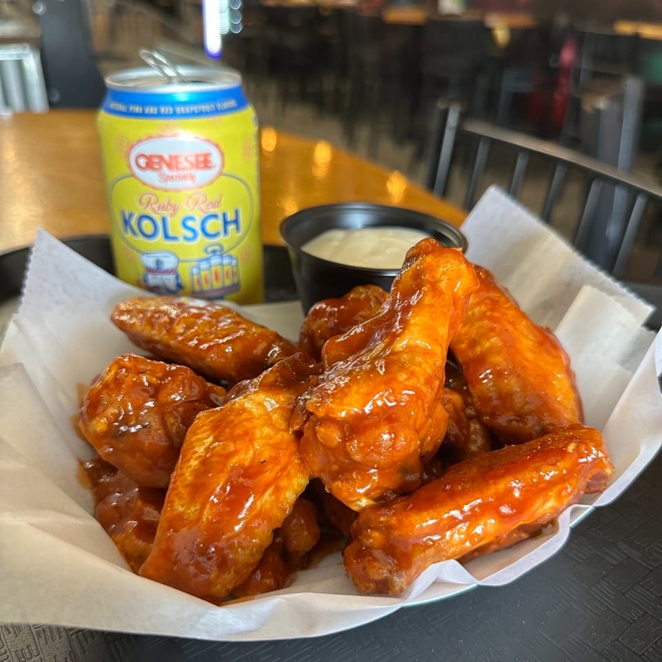 A basket of saucy chicken wings with a side of ranch and a Genesee Ruby Red Kolsch beer.